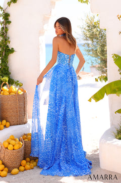 A woman in a blue leopard-print strapless gown stands beside baskets of lemons in a Mediterranean-style setting.