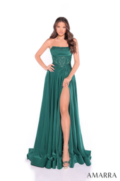 A model wears a strapless emerald green gown with lace bodice and high slit on white background.