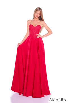 A woman wears a strapless, floor-length red gown with a lace bodice and flowing skirt.