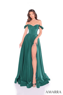 A woman wears an emerald green off-shoulder gown with a high slit and flowing skirt on a white background.