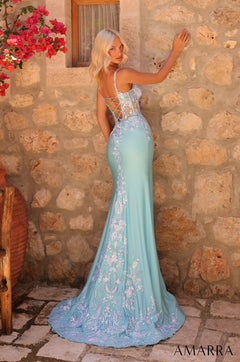A light blue mermaid gown with floral embroidery, corset back, posing against a stone wall with red bougainvillea.