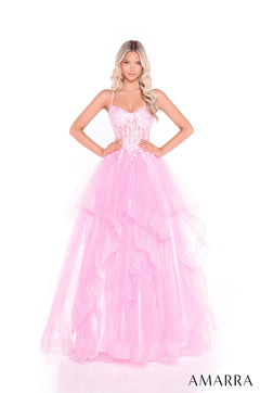 A woman wears a strapless, floor-length Pink ball gown with a corset bodice and tiered, ruffled skirt.