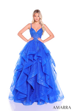 A model wears a Royal Blue ruffled ball gown with a sweetheart neckline and intricate embroidered bodice.
