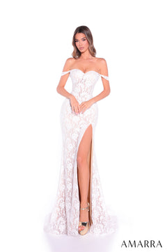 A woman wears an Ivory/Nude off-shoulder lace gown with a high slit, posing against a white background.