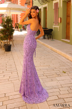 A woman in a purple lace mermaid gown poses confidently on a stone street, wearing a flower in her hair.