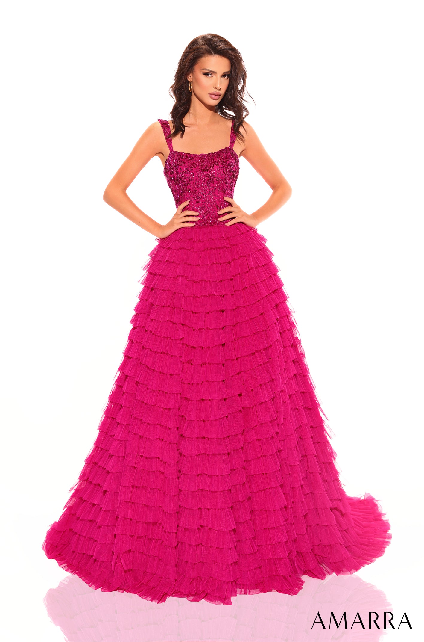 A woman wears a floor-length, ruffled Bright Fuchsia ball gown with an embellished bodice.