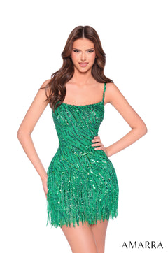 A model wears a short, emerald green sequined dress with a fitted bodice and fringe skirt.