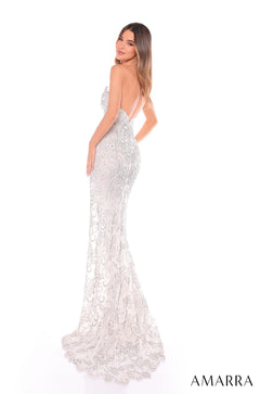 A white lace mermaid gown with sparkling beaded details, worn by a woman facing sideways on a white background.