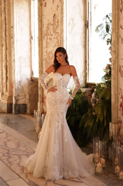 A bride in a lace mermaid wedding gown poses in a vintage room with candles and greenery.