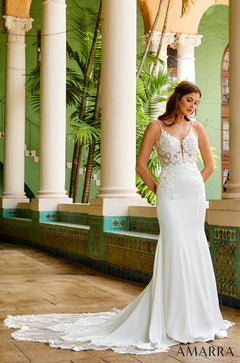 A bride in a white lace mermaid wedding dress poses among columned arches with tropical greenery.
