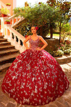 A woman wears a wine/gold butterfly-embellished ballgown on stone steps with garden backdrop.