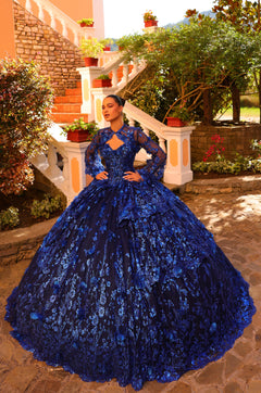 A woman in a voluminous Royal Blue lace ball gown stands on a stone terrace with garden stairs.