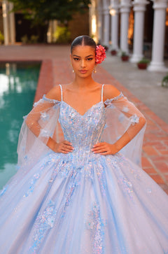 A model wears a sparkling light blue ball gown with floral details and a red flower in her hair.
