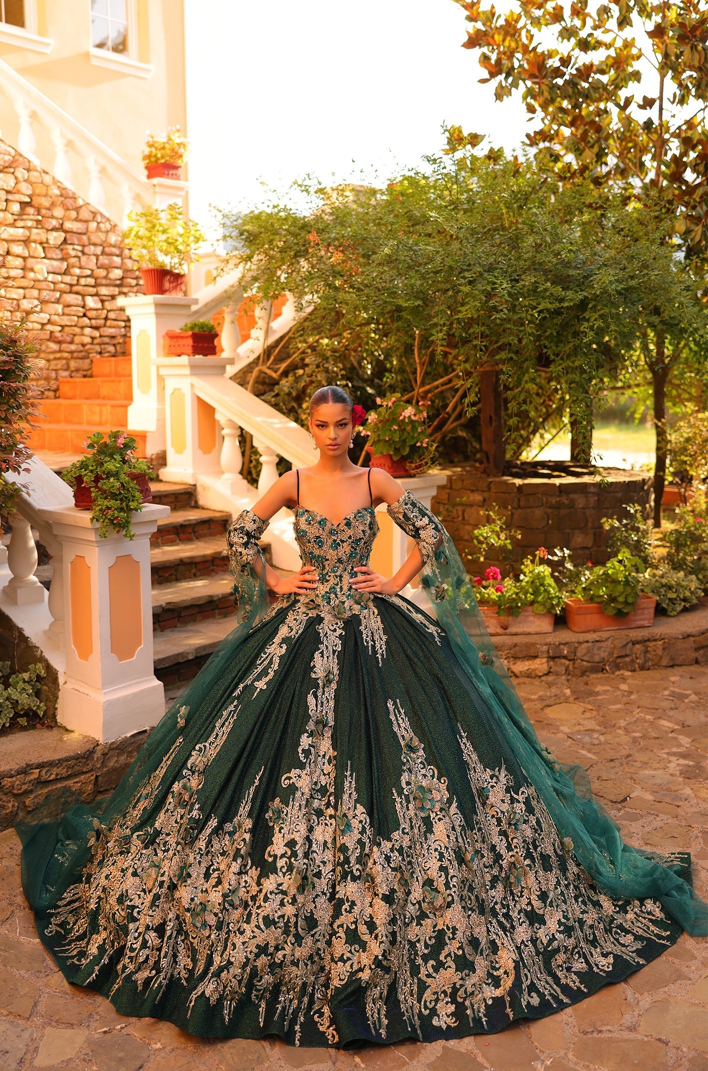A woman wears an elaborate emerald ball gown with intricate gold lace detailing.