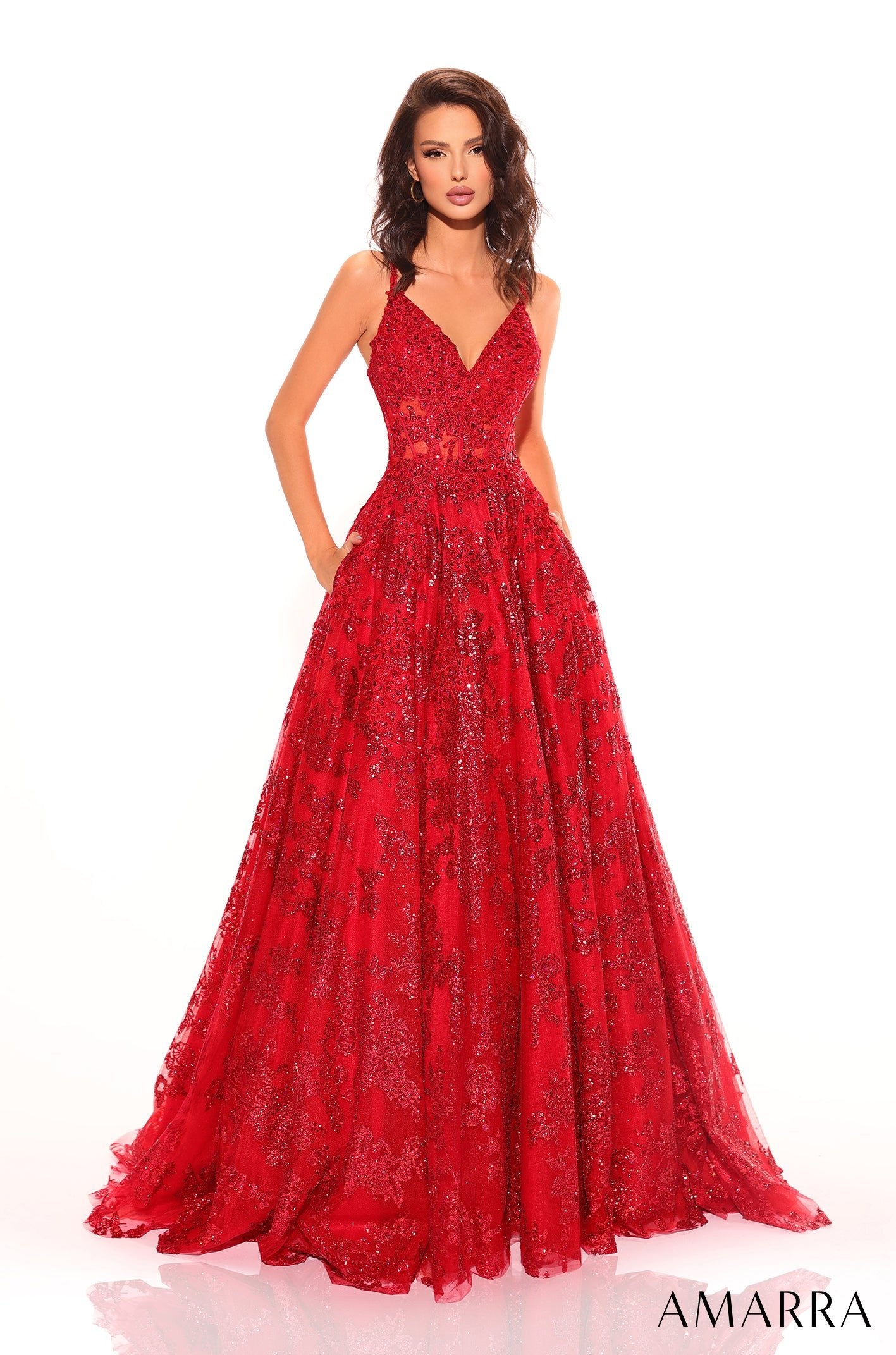 A sparkling red ball gown with a plunging neckline and full, embellished skirt worn by a model.