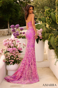 A woman wears a vibrant pink lace mermaid gown, posing among flowers and cacti in an outdoor setting.