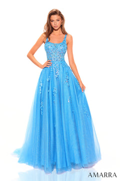 A woman wears a turquoise ball gown with floral embellishments and a flowing tulle skirt by Amarra.