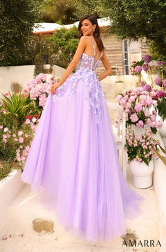 A woman in a lavender ball gown stands among pink flowers in a garden setting.