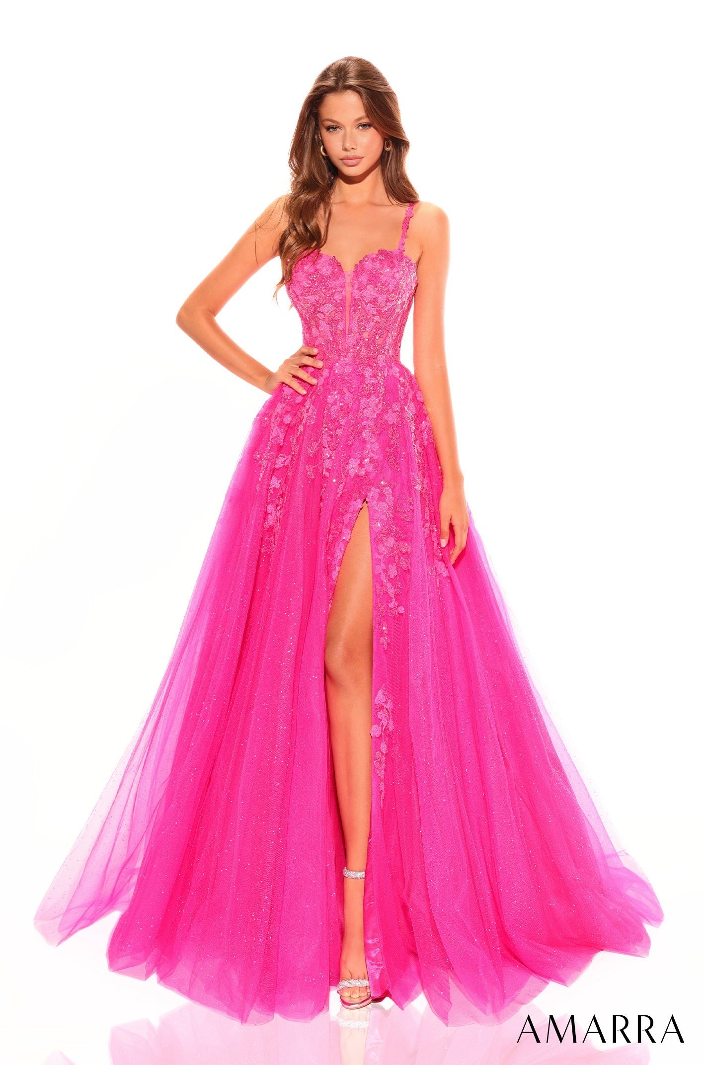 A model wears a fuchsia lace ballgown with a high slit and sweetheart neckline.