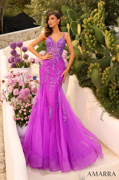 A woman wears a shimmering magenta mermaid gown with floral embroidery, posing among pink flowers and cacti.