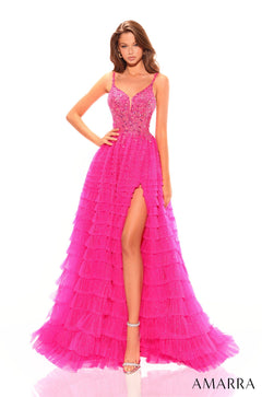A slender model wears a fuchsia tiered tulle gown with beaded bodice and high slit on white background.