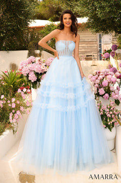 A woman wears a light blue strapless ball gown, standing amid pink and purple flowers in a garden setting.