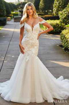 A blonde model wears an off-shoulder white lace mermaid wedding gown with a flowing tulle skirt.