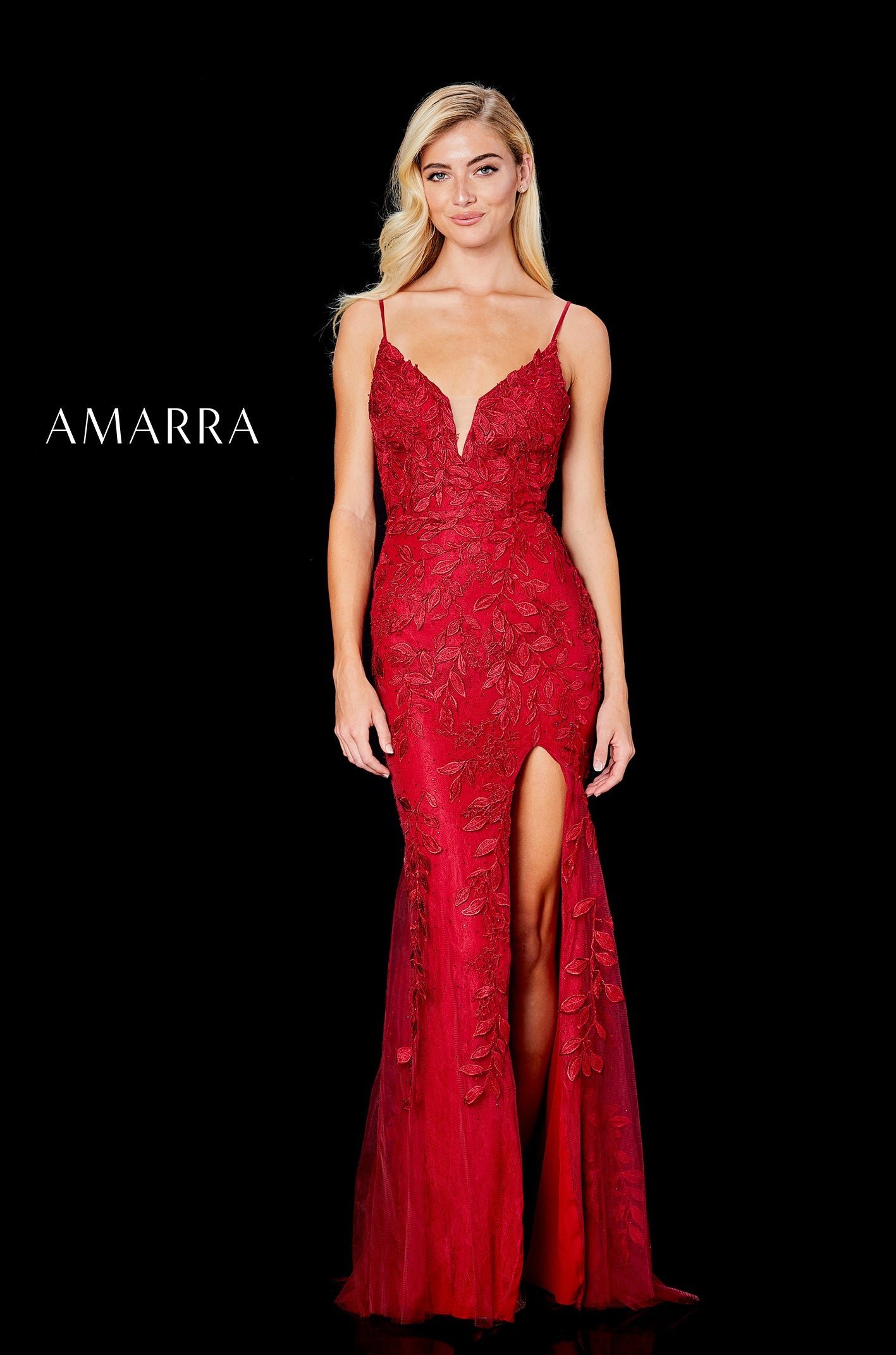 A blonde model wears a floor-length red lace gown with a plunging neckline and high side slit.