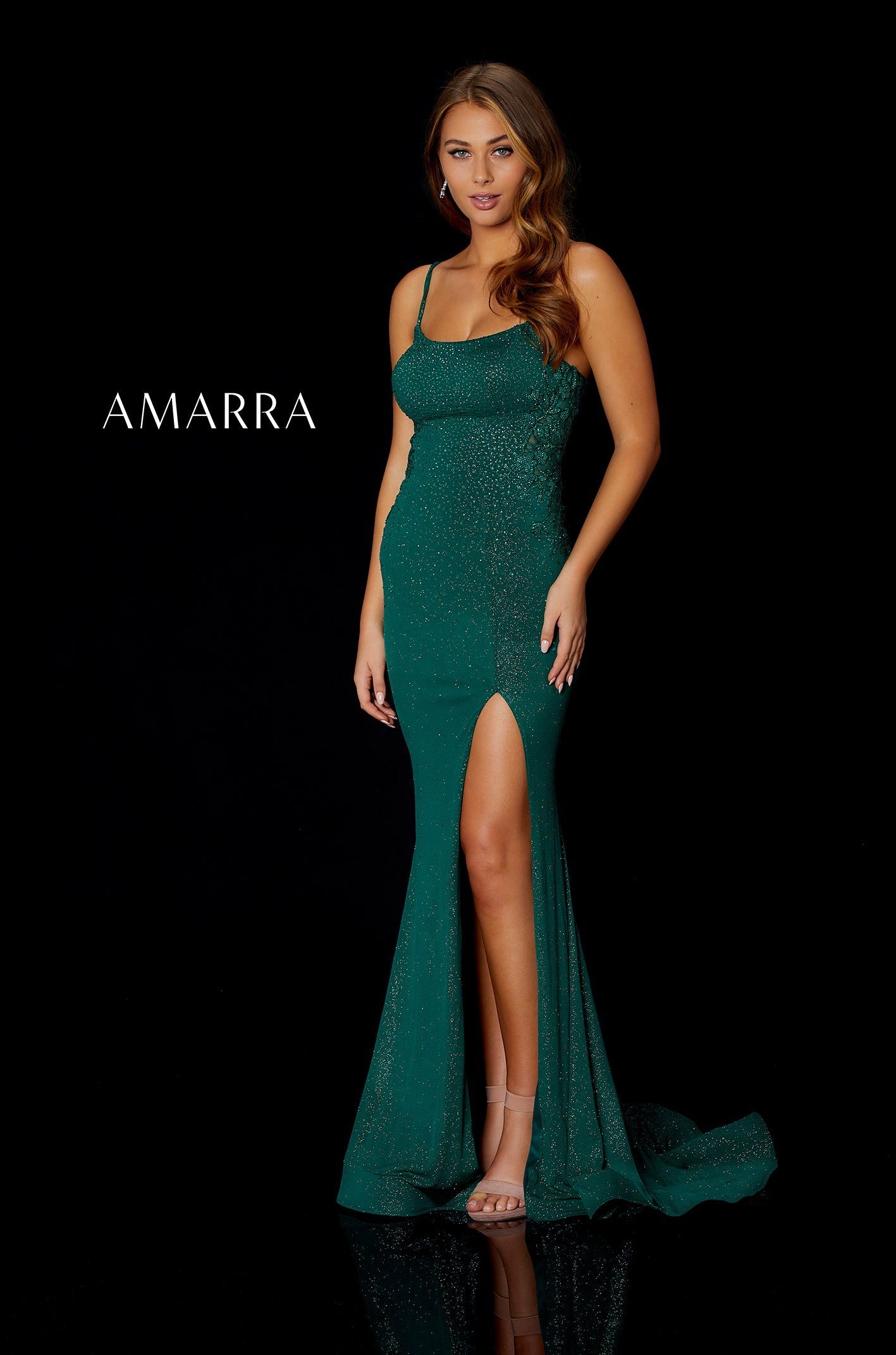 A model wears a shimmering emerald green gown with a high slit and thin straps.
