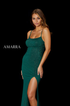 A model wears a shimmering emerald green evening gown with a high slit and thin straps against a black background.