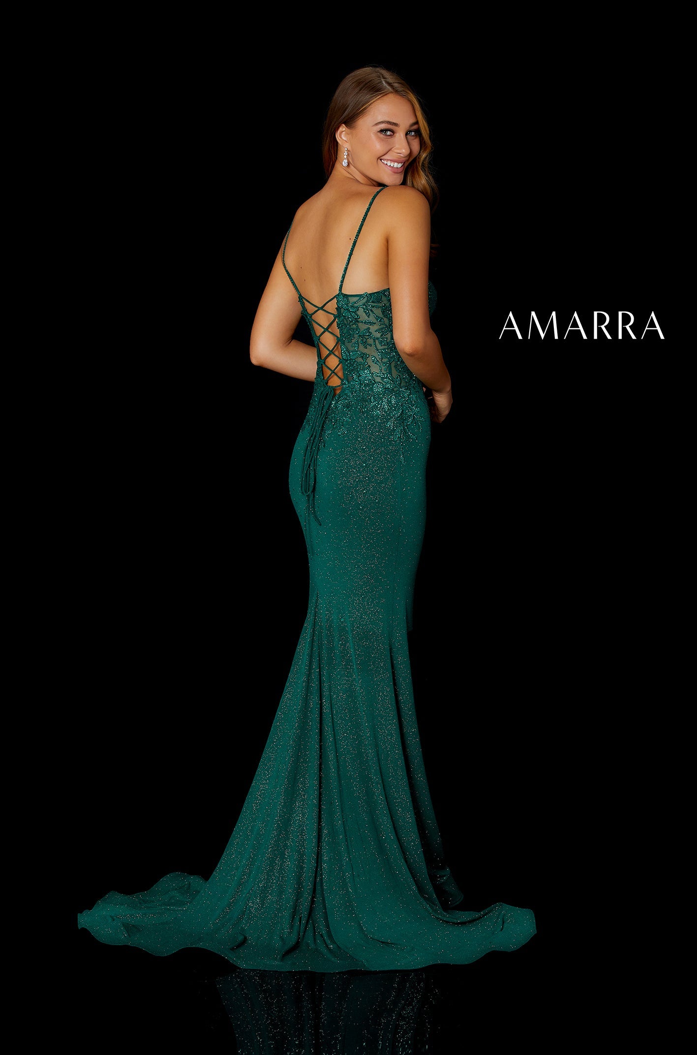 A model wears a shimmering emerald green mermaid-style gown with a corset back and long train.
