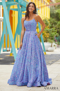 A woman in a sparkling blue and purple sequin ball gown stands confidently against a colorful background.