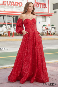 A woman wears a sparkling red off-shoulder ball gown with puffy sleeves in front of a hotel.