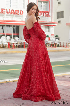 A woman wears a sparkly red off-shoulder gown, posing elegantly in front of a motel sign.