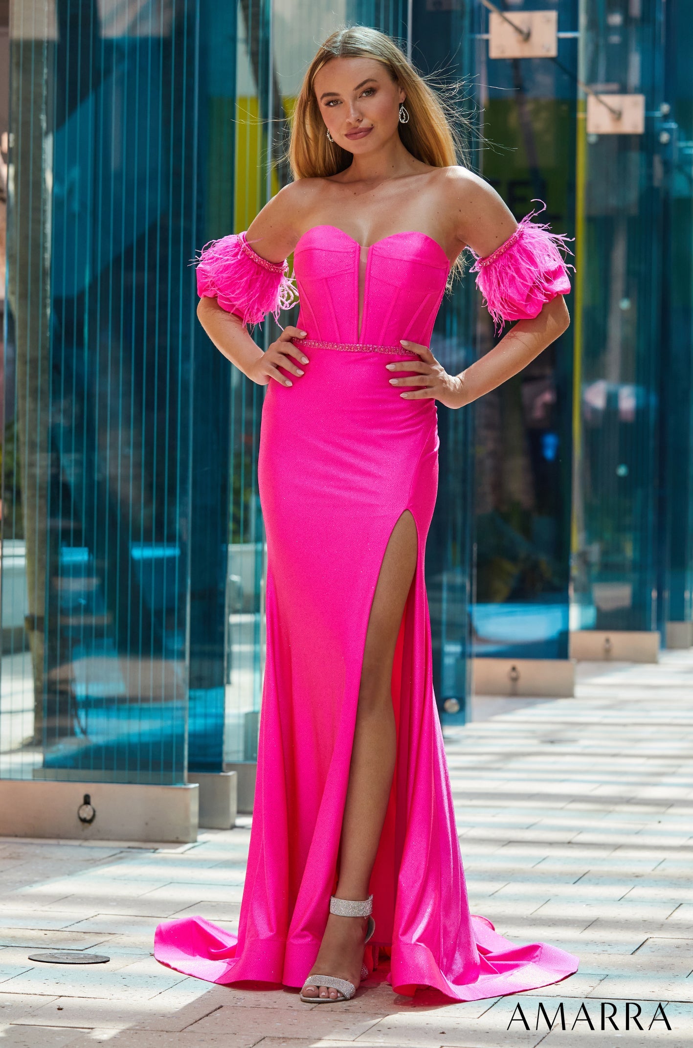 A vibrant pink strapless gown with feathered sleeves and a high slit, worn with silver heels.