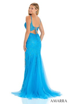 A woman wears a long, sparkly blue tulle gown with a corset back, posing from the side.