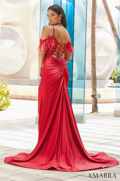 A woman wears a vibrant red feathered gown with a corset back and sweeping train.