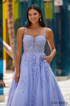 A woman wears a lavender lace ballgown with floral embroidery and a sweetheart neckline.