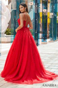 A woman wears a vibrant red ball gown with a lace bodice and criss-cross back straps.