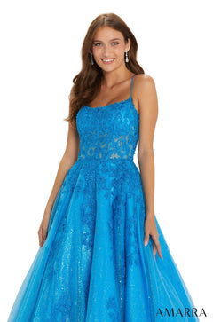 A woman models a bright blue sparkly ball gown with spaghetti straps and a fitted bodice from Amarra.