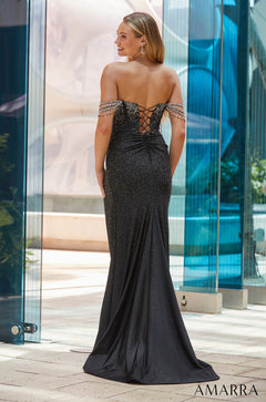 A blonde woman in a sparkling black off-shoulder gown stands before glass walls, facing away with a corset back.