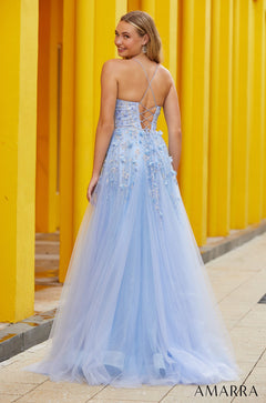 A light blue tulle gown with floral embellishments and a criss-cross back, photographed against a yellow striped wall.