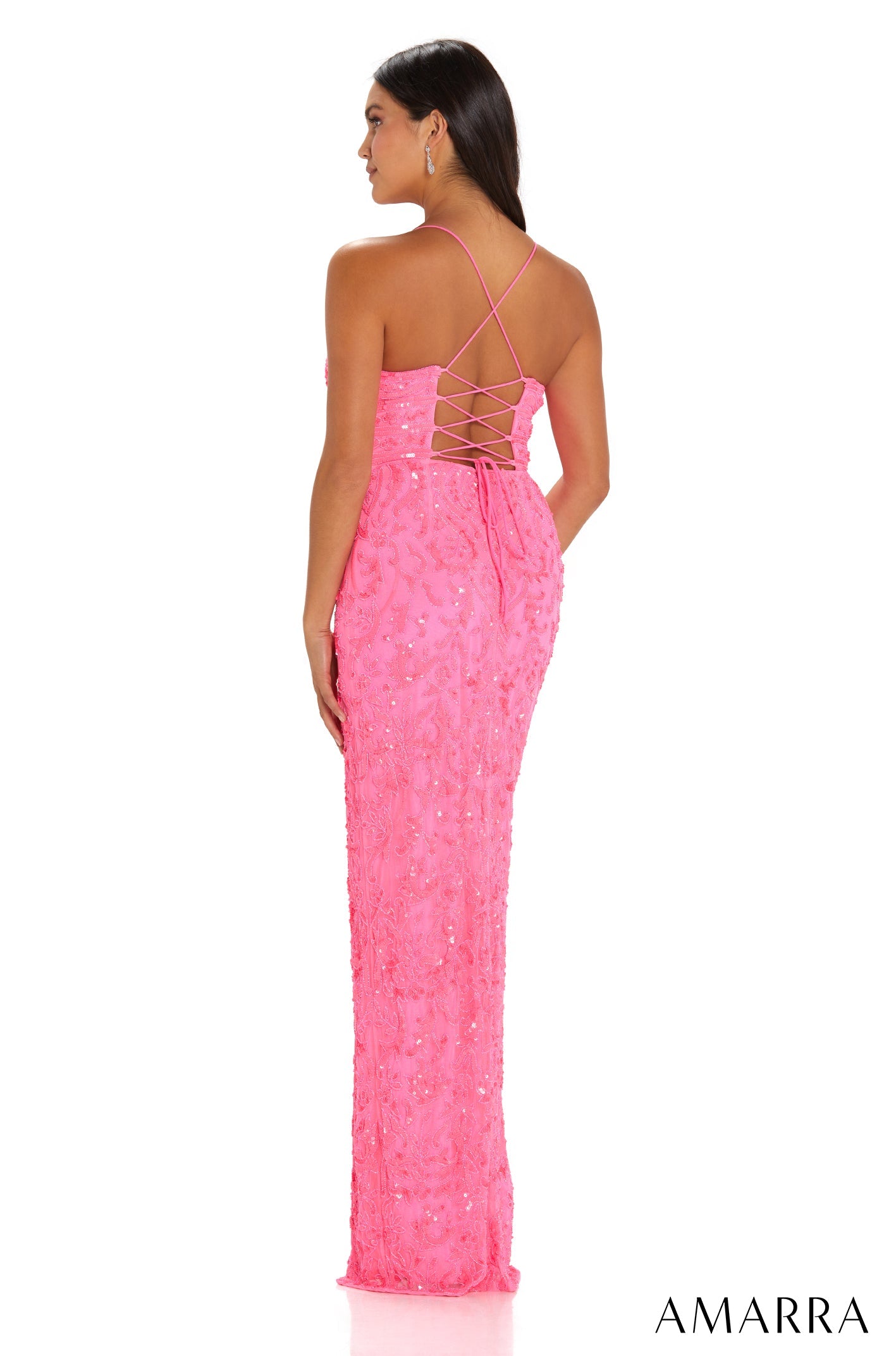 A woman wears a long, hot pink sequined dress with a criss-cross back, viewed from behind.