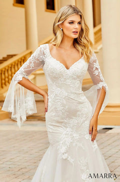 Blonde model wears white lace wedding dress with flared sleeves, standing on ornate stone steps.