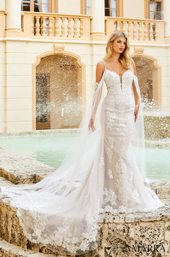 A bride in an elegant white lace mermaid wedding dress with long train stands by a fountain near a classical building.