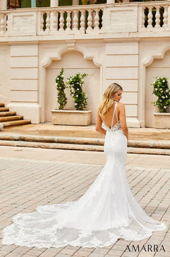 A bride in a white lace mermaid wedding dress stands on stone steps, facing away to show her low back and train.