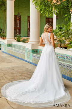 A white lace wedding dress with a long train, photographed from behind in a Mediterranean-style tiled courtyard.